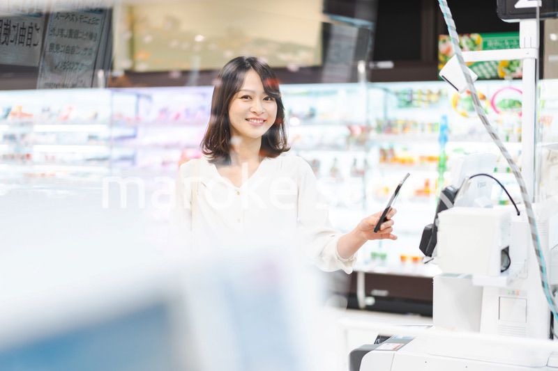 スーパーでスマホ決済を使う若い女性
