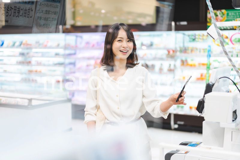 スーパーでスマホ決済を使う若い女性