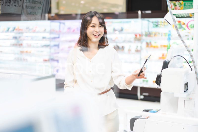 スーパーでスマホ決済を使う若い女性