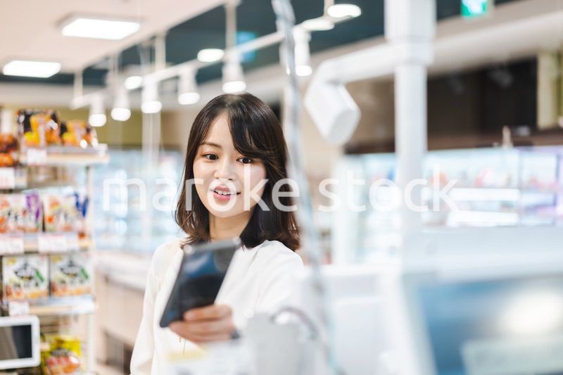 スーパーでスマホ決済を使う若い女性