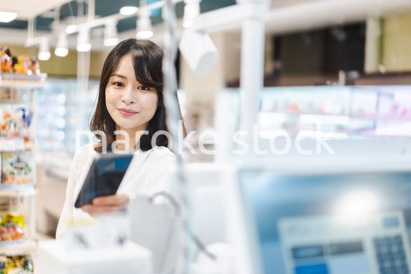 スーパーでスマホ決済を使う若い女性