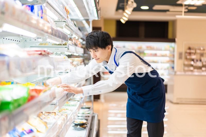 食品スーパーで品出しをする若いスタッフ