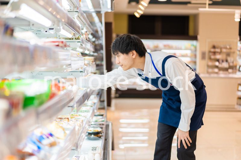 食品スーパーで品出しをする若いスタッフ