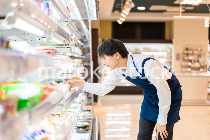 食品スーパーで品出しをする若いスタッフ