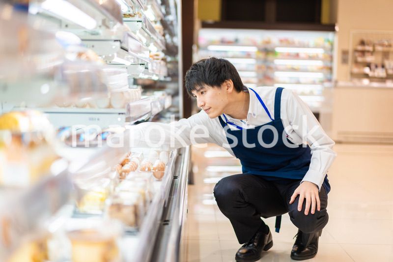 食品スーパーで品出しをする若いスタッフ