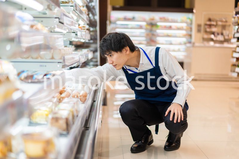 食品スーパーで品出しをする若いスタッフ