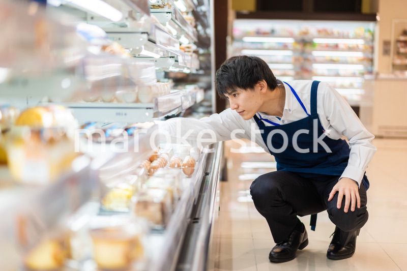 食品スーパーで品出しをする若いスタッフ