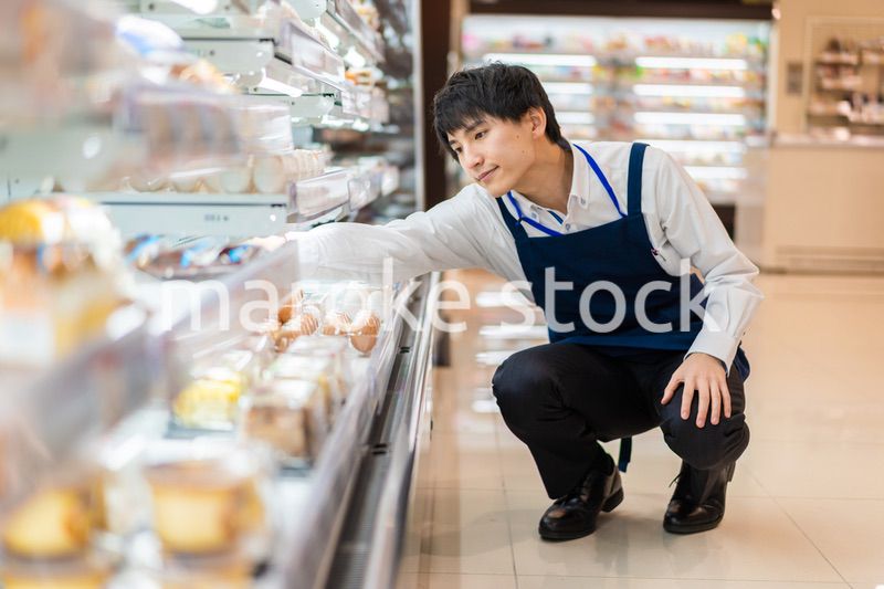 食品スーパーで品出しをする若いスタッフ