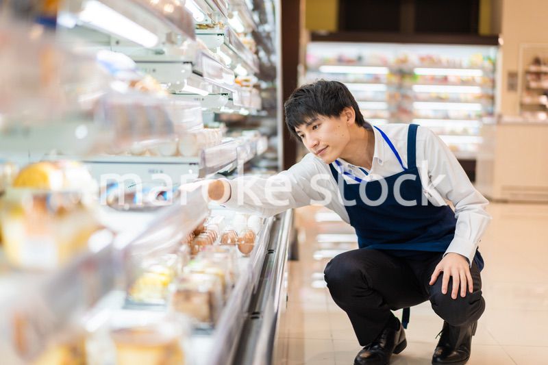 食品スーパーで品出しをする若いスタッフ