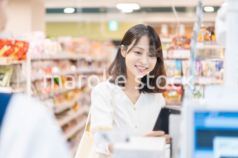 スーパーでスマホ決済を使う若い女性