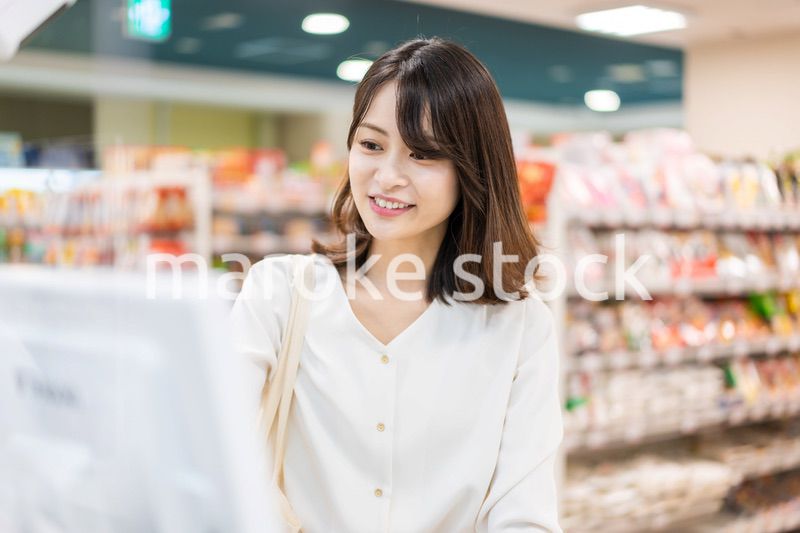 スーパーでスマホ決済を使う若い女性