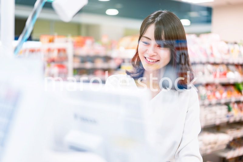 スーパーでスマホ決済を使う若い女性