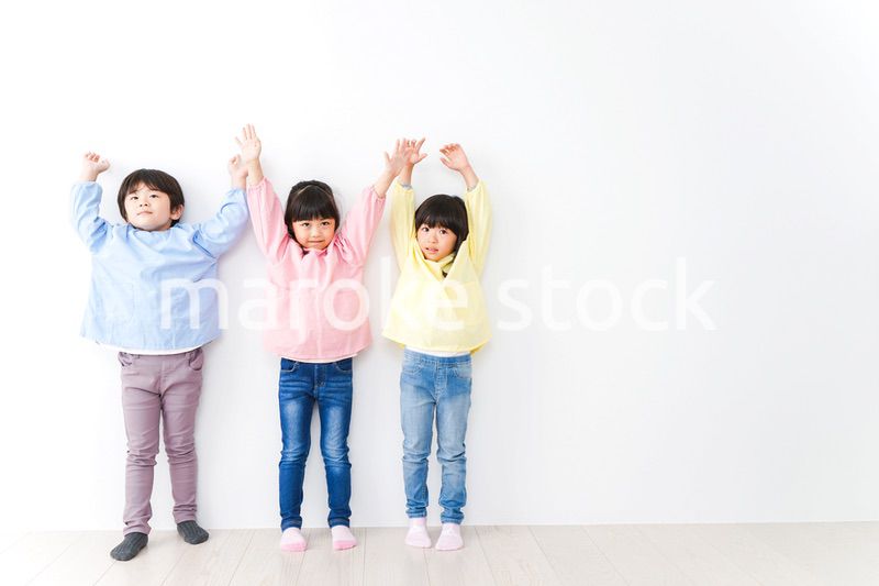 壁に並ぶ3人の幼稚園児