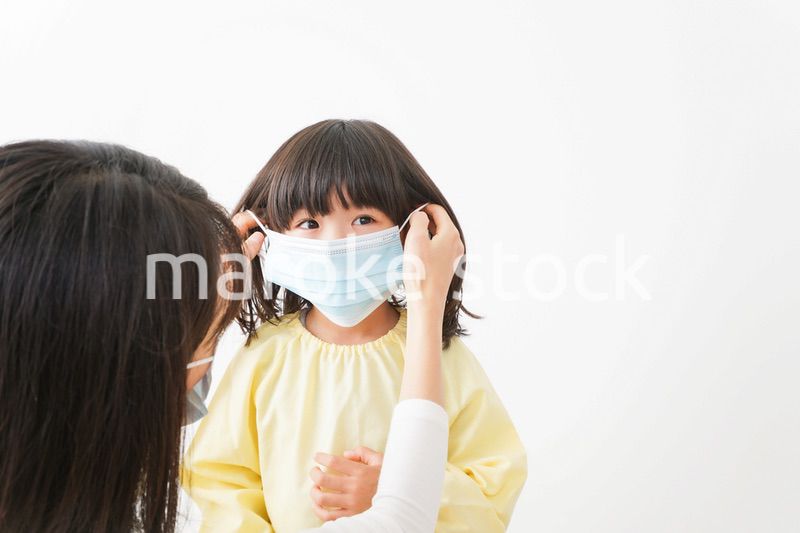 子供にマスクをつける保育士