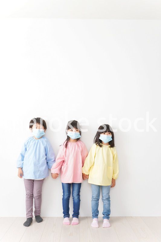 マスクをつけて手を繋ぐ幼稚園児