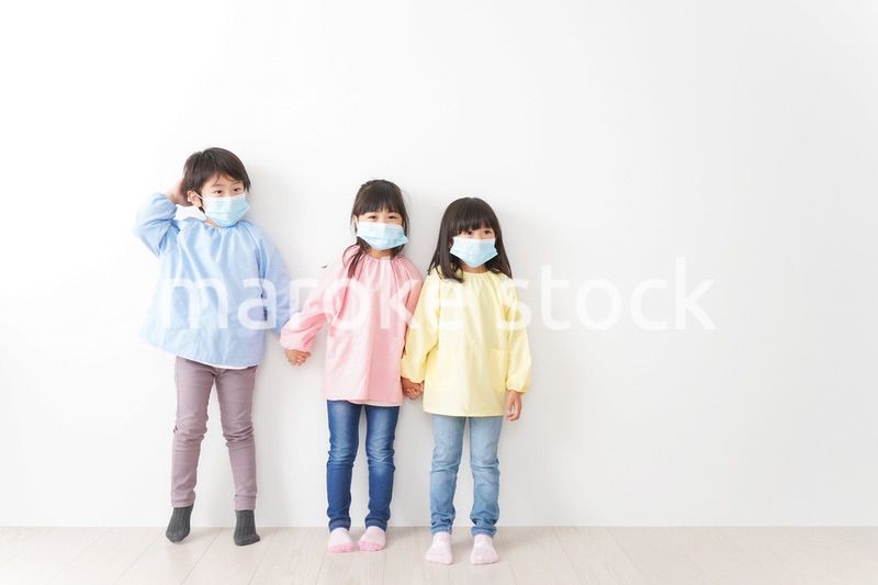 マスクをつけて手を繋ぐ幼稚園児