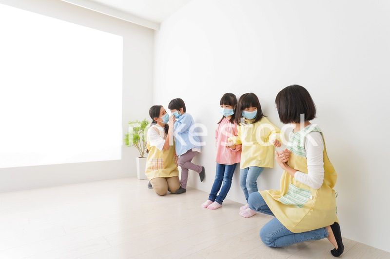 マスクを付けて幼稚園で遊ぶ子どもたちの先生