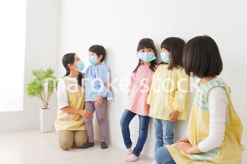 マスクを付けて幼稚園で遊ぶ子どもたちの先生