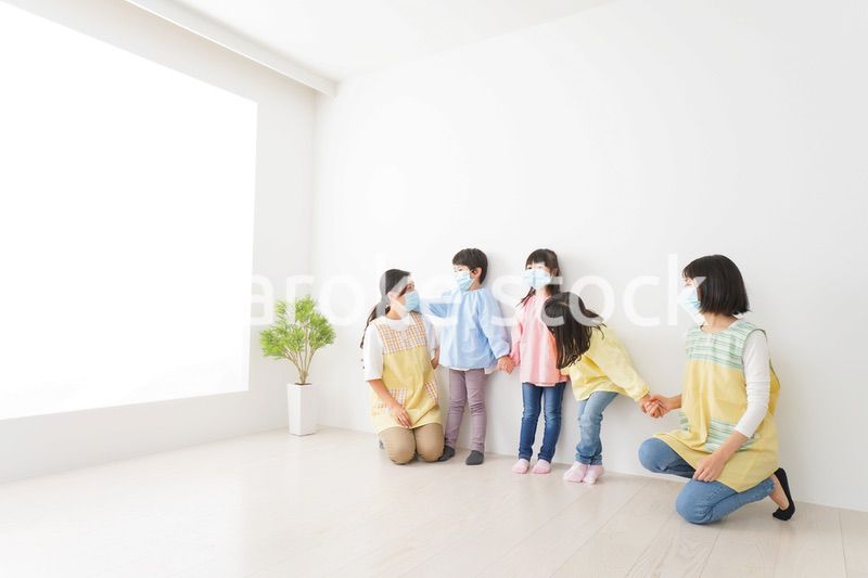 マスクを付けて幼稚園で遊ぶ子どもたちの先生