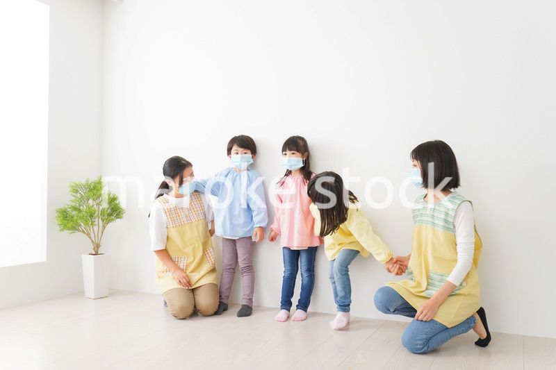 マスクを付けて幼稚園で遊ぶ子どもたちの先生