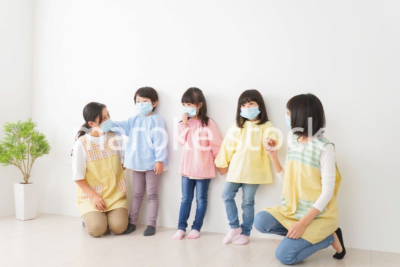 マスクを付けて幼稚園で遊ぶ子どもたちの先生