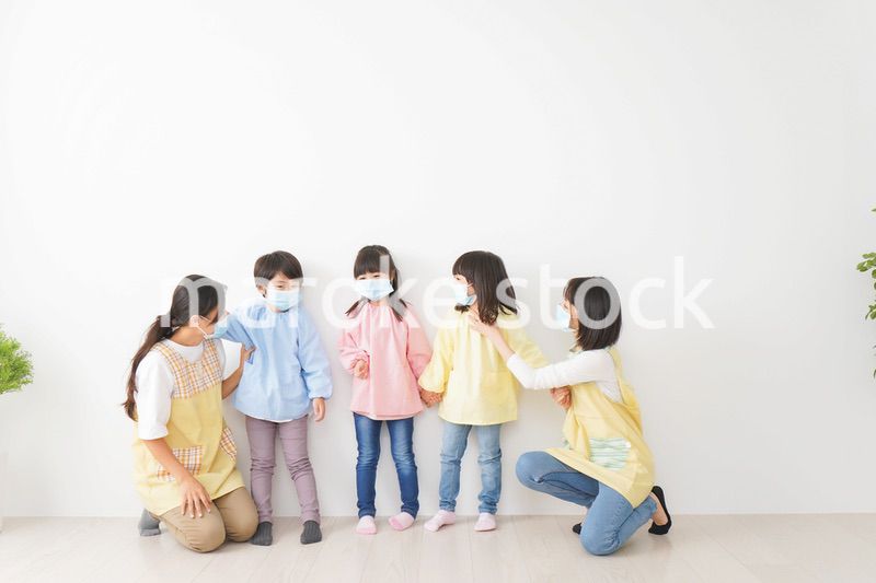 マスクを付けて幼稚園で遊ぶ子どもたちの先生