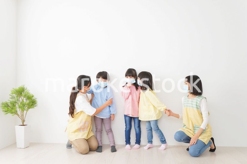 マスクを付けて幼稚園で遊ぶ子どもたちの先生