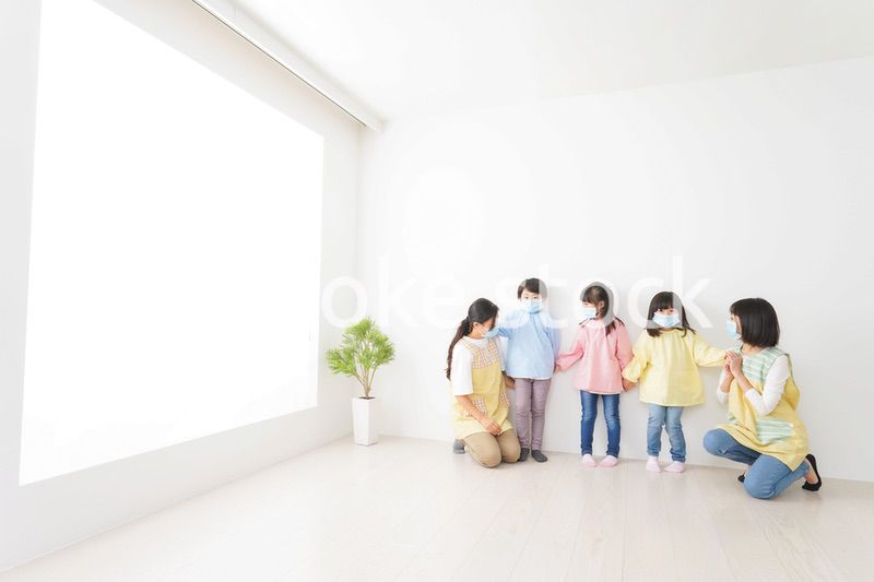 マスクを付けて幼稚園で遊ぶ子どもたちの先生