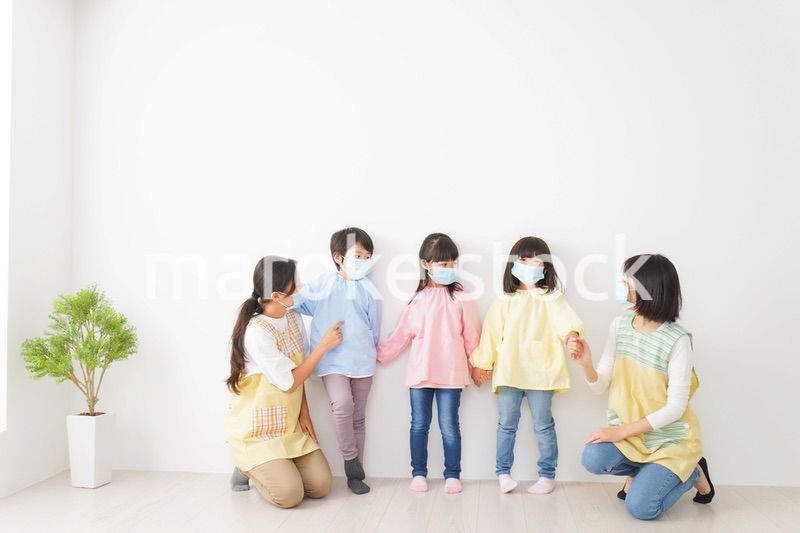 マスクを付けて幼稚園で遊ぶ子どもたちの先生