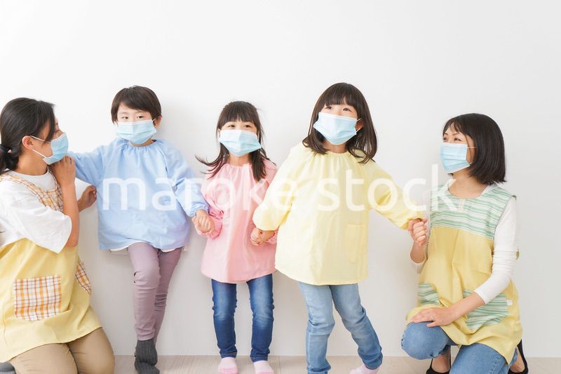 マスクを付けて幼稚園で遊ぶ子どもたちの先生