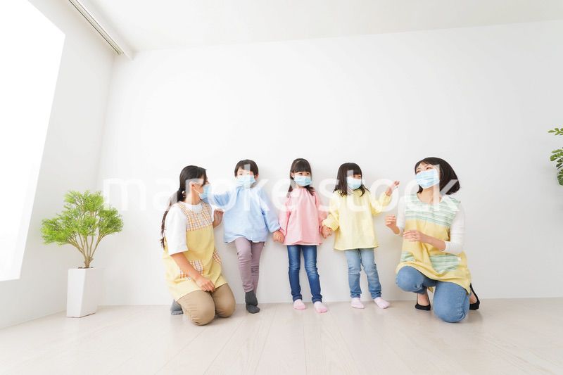 マスクを付けて幼稚園で遊ぶ子どもたちの先生