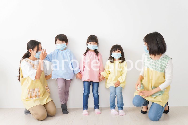 マスクを付けて幼稚園で遊ぶ子どもたちの先生