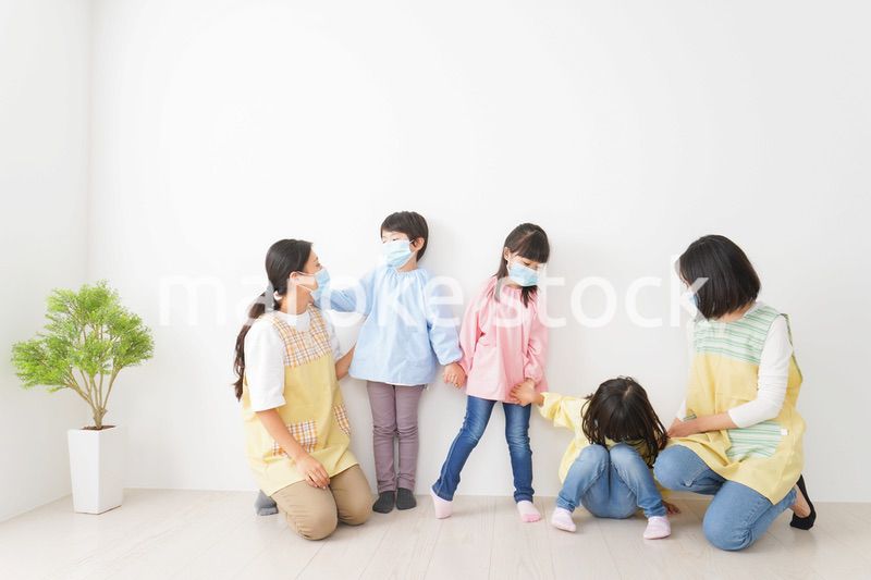 マスクを付けて幼稚園で遊ぶ子どもたちの先生