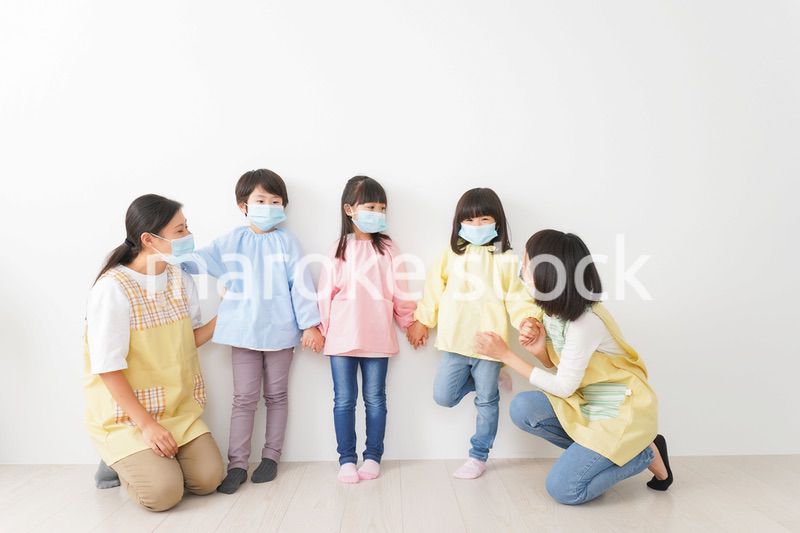 マスクを付けて幼稚園で遊ぶ子どもたちの先生