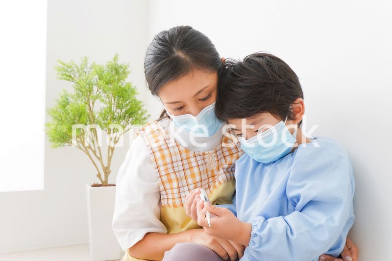 体温を測定する子供と幼稚園の先生