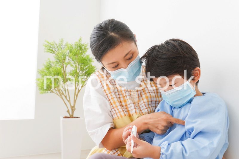 体温を測定する子供と幼稚園の先生