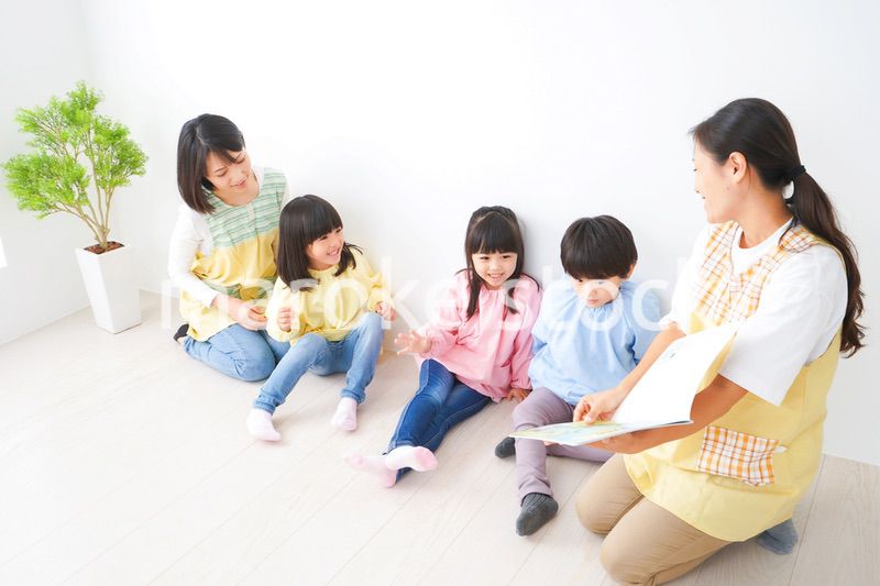 絵本の読み聞かせをする保育士と子どもたち