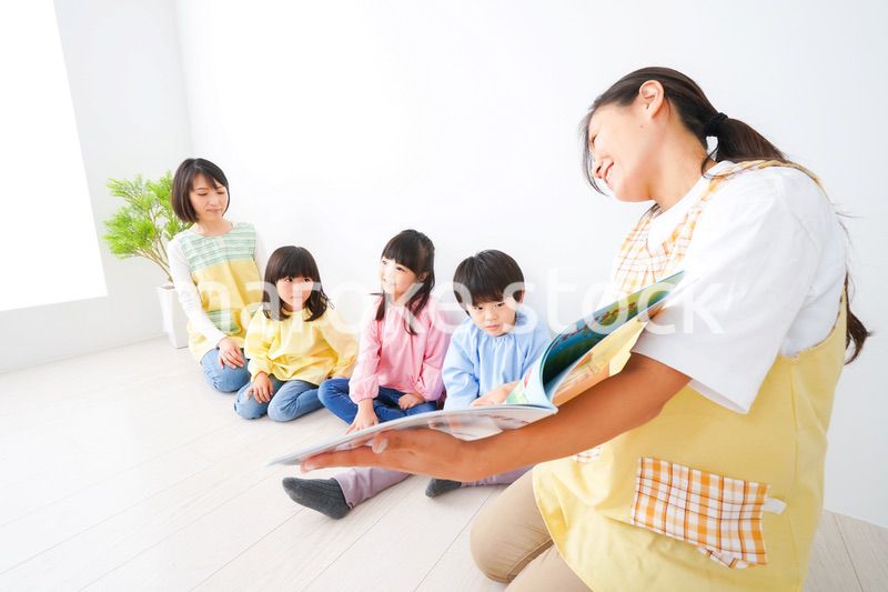 絵本の読み聞かせをする保育士と子どもたち