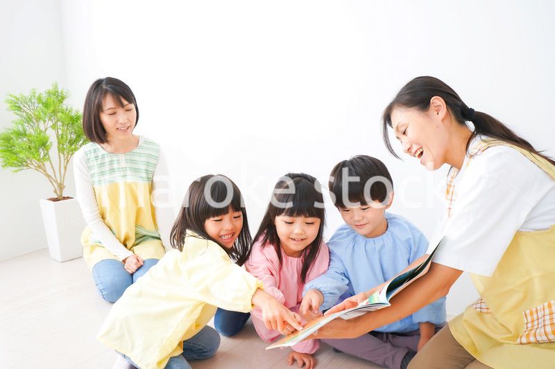 絵本の読み聞かせをする保育士と子どもたち