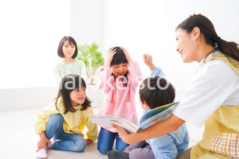 絵本の読み聞かせをする保育士と子どもたち