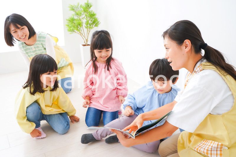 絵本の読み聞かせをする保育士と子どもたち