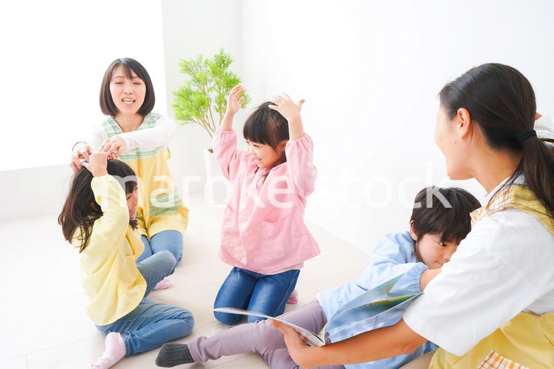 絵本の読み聞かせをする保育士と子どもたち