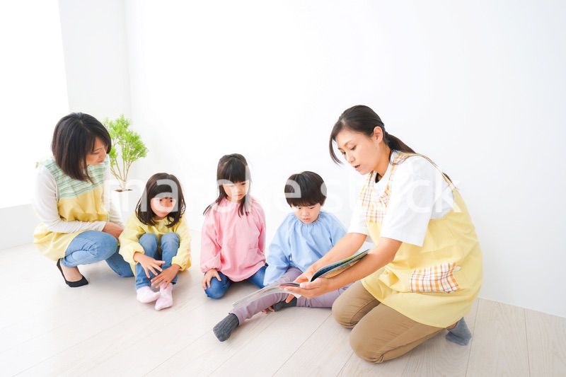 絵本の読み聞かせをする保育士と子どもたち