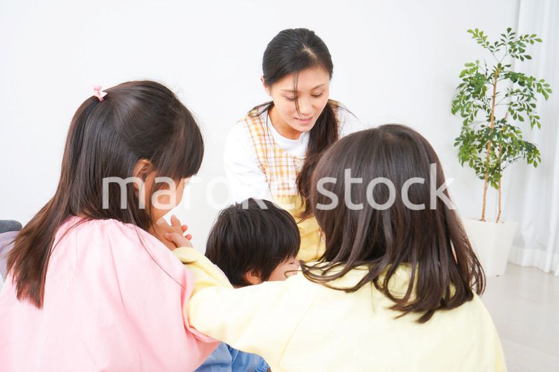 絵本の読み聞かせをする保育士と子どもたち