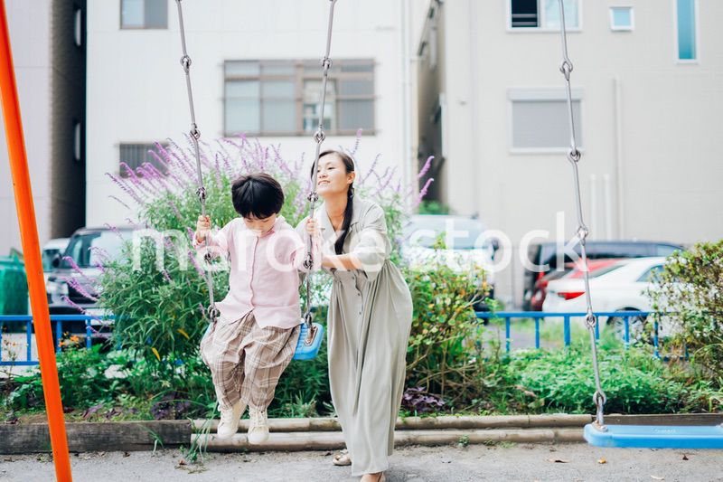 お母さんとブランコに乗る男の子