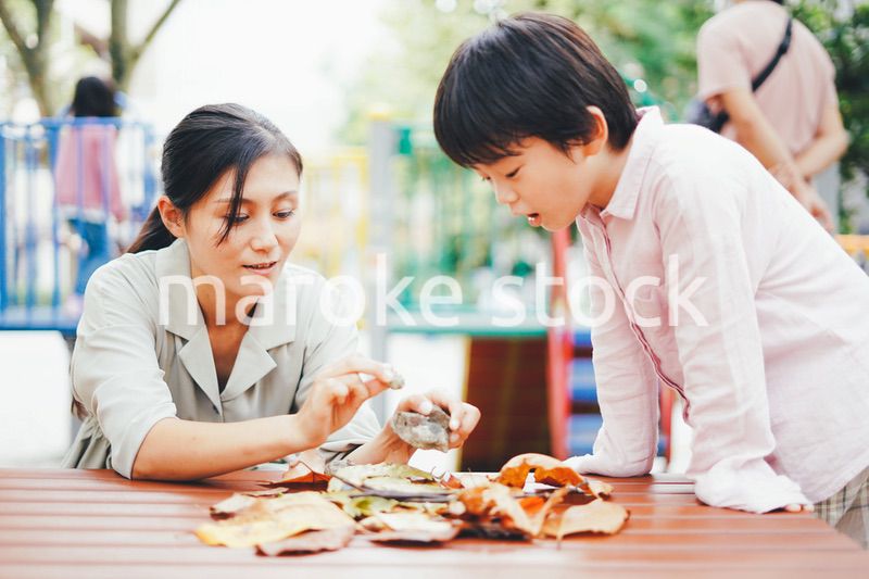 葉っぱで遊ぶお母さんと息子