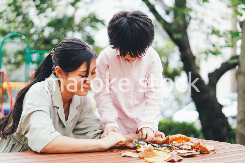 葉っぱで遊ぶお母さんと息子