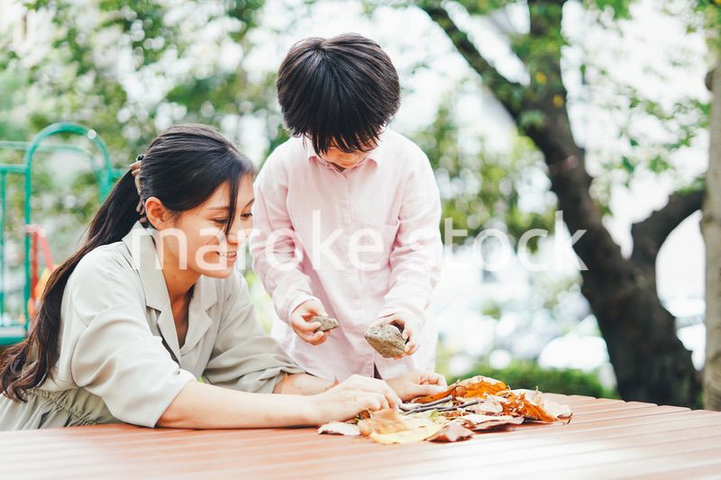 葉っぱで遊ぶお母さんと息子