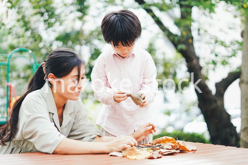 葉っぱで遊ぶお母さんと息子