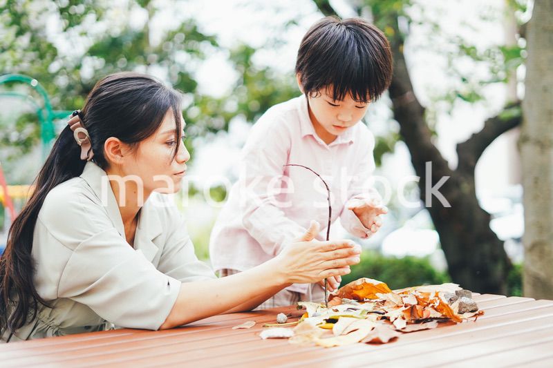 葉っぱで遊ぶお母さんと息子